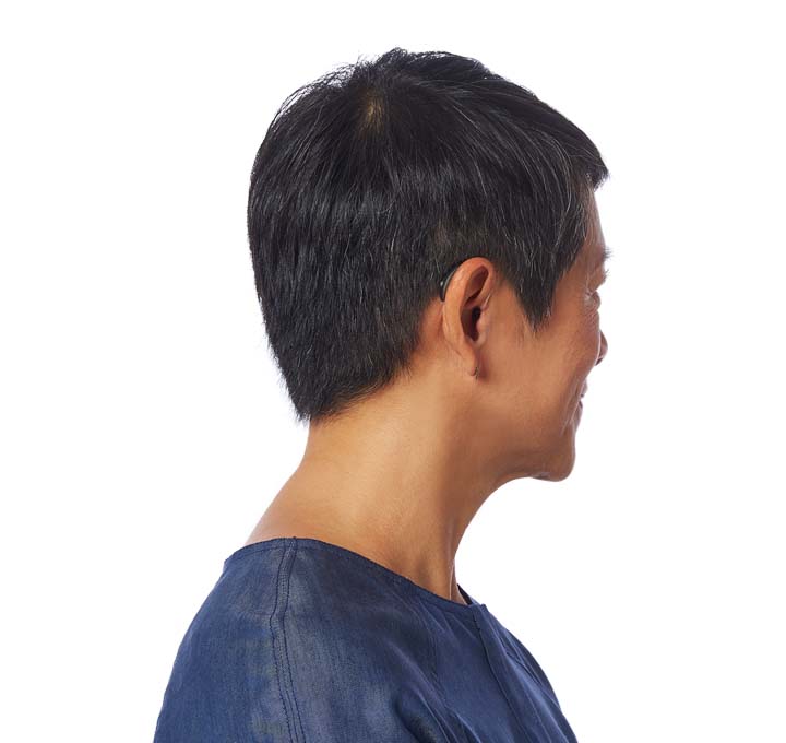 Asian man turning head to the left and showing hearing aid